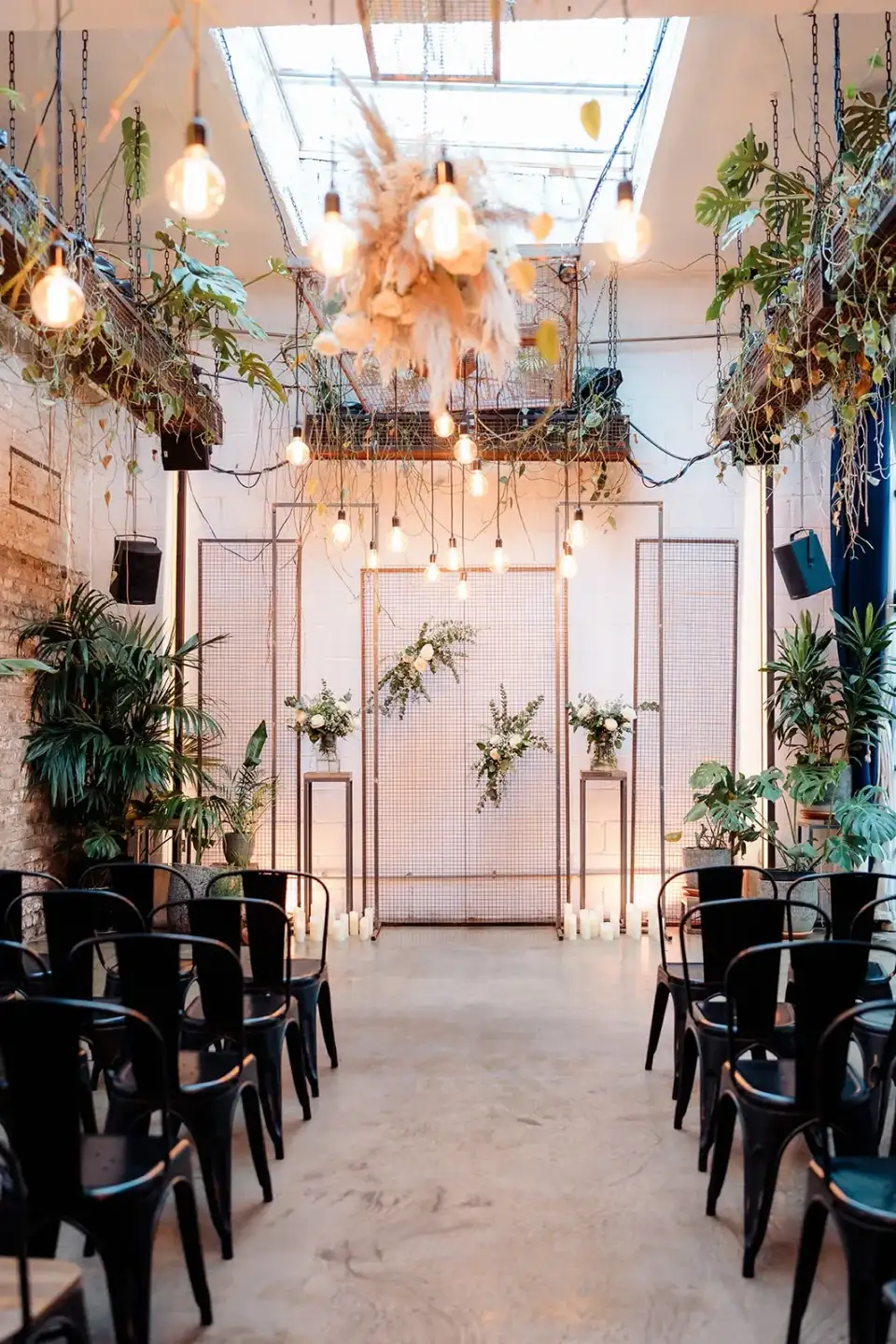 Ceremony chairs facing a frame of hanging bulbs and a dried flower installation in the Winter Garden