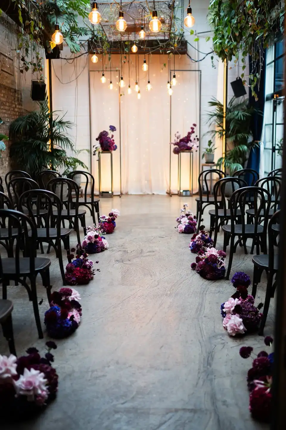 Winter Garden set for a ceremony with rows of bentwood chairs and deep purple flowers along the aisle