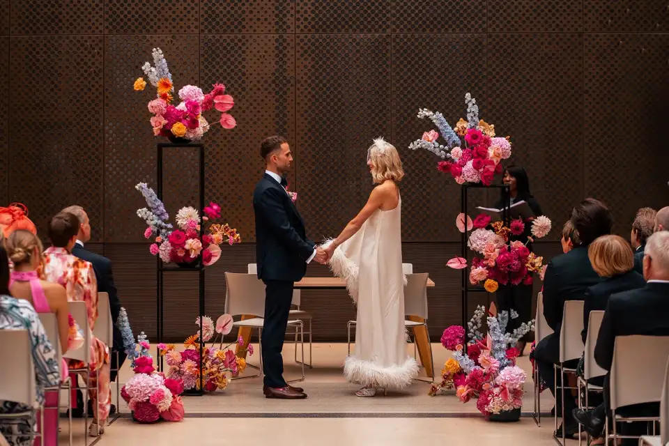 Guests seated either side of the aisle beneath a floral ceremony arch.