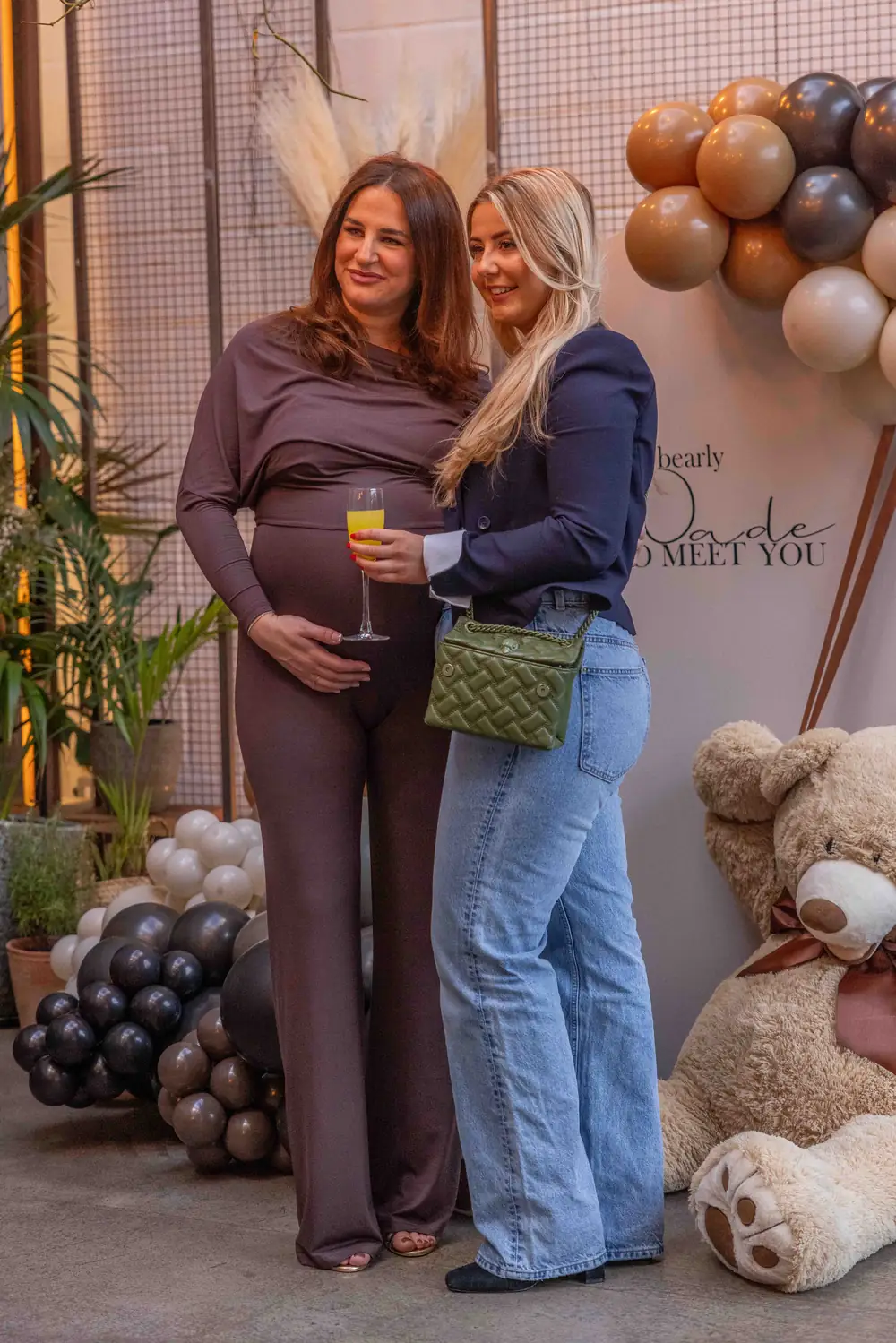Guests celebrating with a glass of fizz beside a giant teddy bear and balloon display at a baby shower at The Hackney