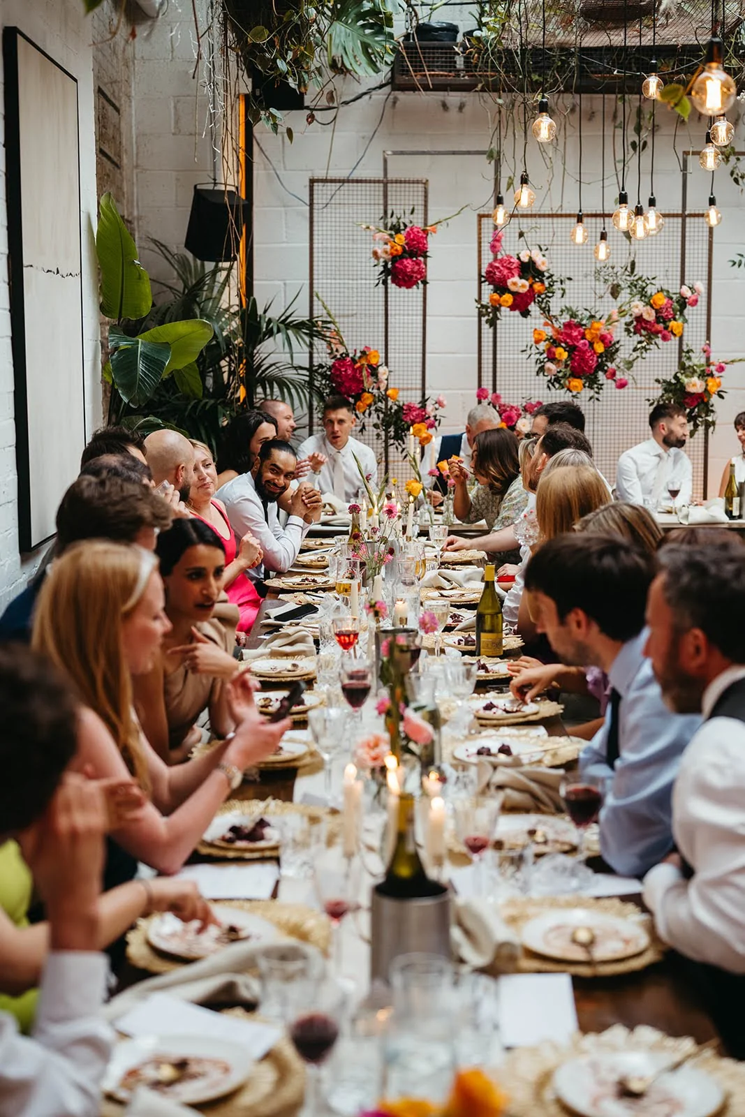 Guests dining at a long candlelit table at an intimate wedding at The Hackney