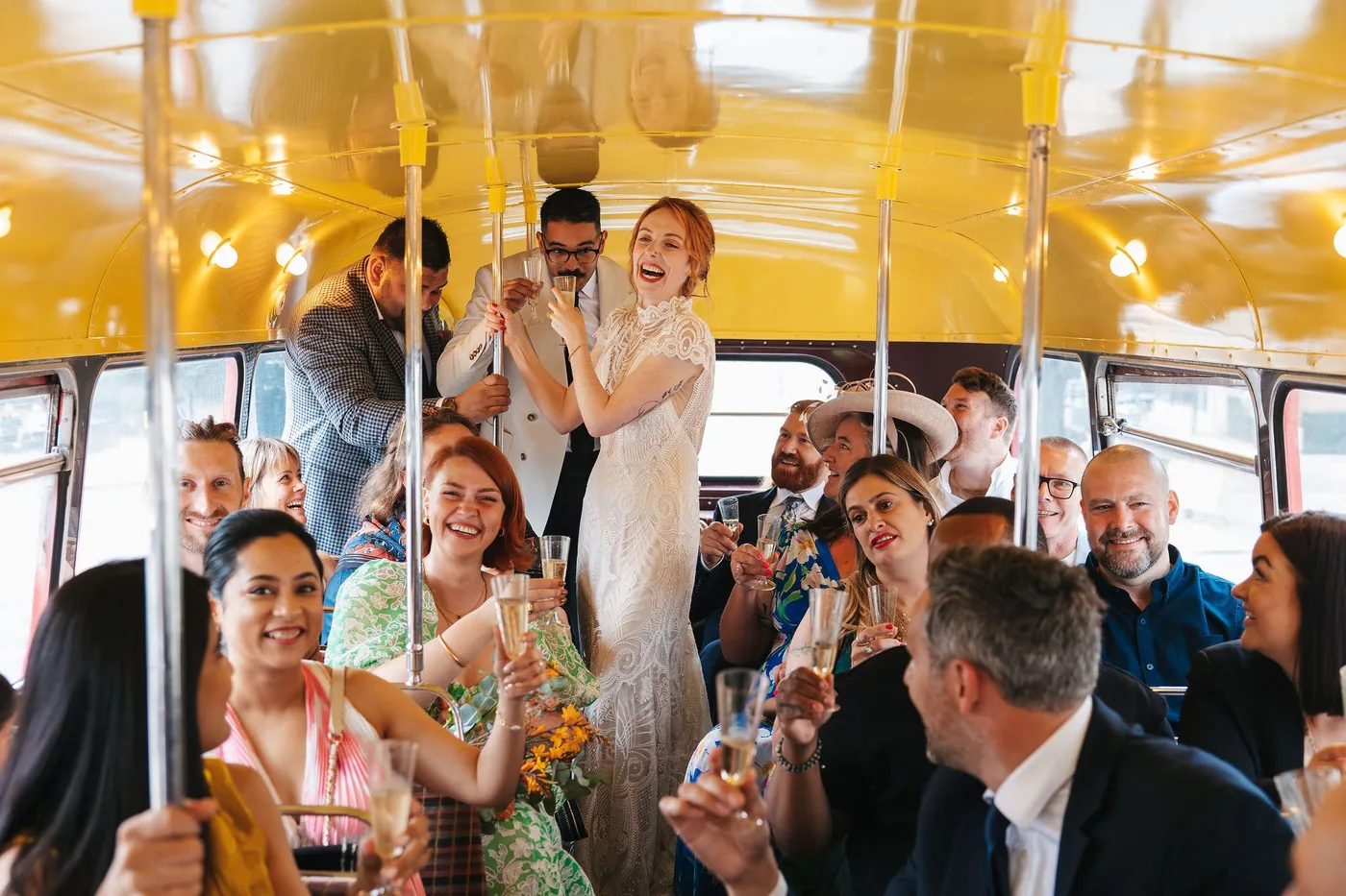 Wedding guests raising champagne glasses aboard the Routemaster on the way to The Hackney
